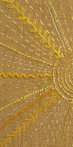 close up view of an embroidered fabric with gold thread on the outside and yellow thread on the inside