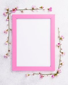 a pink frame sitting on top of a white wall next to some flowers and branches