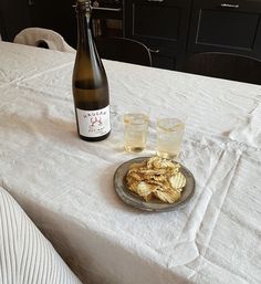 a bottle of wine and two glasses on a table with food in front of it