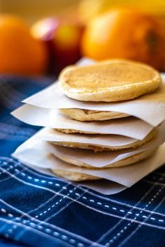 a stack of pancakes sitting on top of a blue table cloth next to oranges