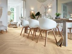 a dining room with white chairs and wood flooring