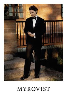 a man in a tuxedo looking at his cell phone while standing on steps