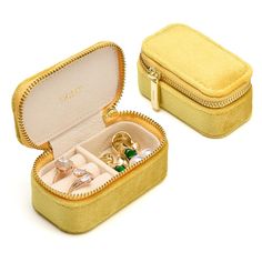 an open jewelry box with rings inside on a white background in front of a yellow case