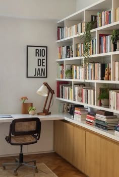 a home office with bookshelves full of books and plants on the desk area