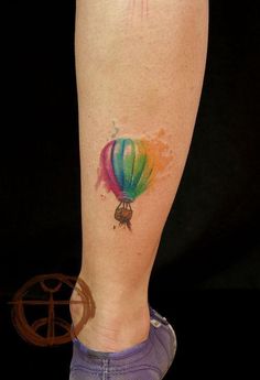 a colorful hot air balloon tattoo on the right leg and foot, painted with watercolors