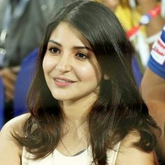 a woman sitting in front of a crowd with her hand on her hip and looking at the camera