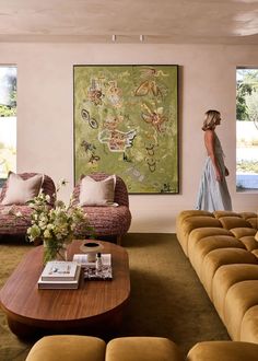 a woman standing in the living room looking at an art work on the wall behind her