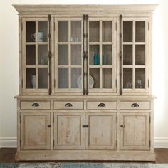 an old china cabinet with glass doors and drawers on the front, against a white wall