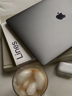 an apple laptop sitting on top of a table next to a glass of ice water