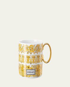 a yellow and white coffee cup with ornate designs on the outside, in front of a light gray background