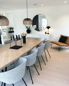 a dining room table with chairs and mirrors on the wall above it, in front of a mirror