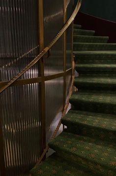 an image of a stair case with green carpet and metal railings on the bottom