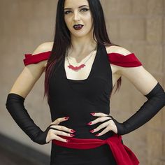 a woman dressed in black and red poses with her hands on her hips