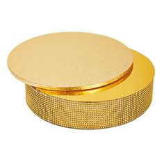 a round gold box with a mesh design on the lid and bottom, sitting on a white surface