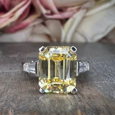 a fancy yellow diamond ring sitting on top of a wooden table