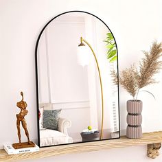 a mirror sitting on top of a wooden shelf next to a vase with a plant