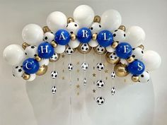 a bunch of balloons that are hanging on the wall with letters and soccer balls attached to them