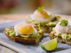 an egg and avocado sandwich on toast with lime wedges