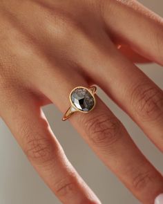 a woman's hand wearing a ring with a black diamond in the center and gold band