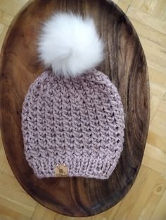 a crocheted hat with a white pom - pom on top of it