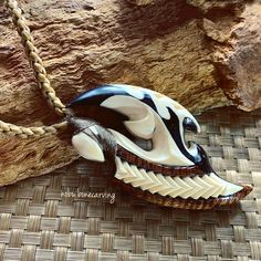 a white and black animal's head is on a brown woven surface next to a rock