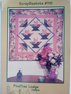 a quilted wall hanging with pink flowers in front of it