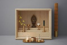 a wooden box with candles and a buddha statue in the middle on a grey surface