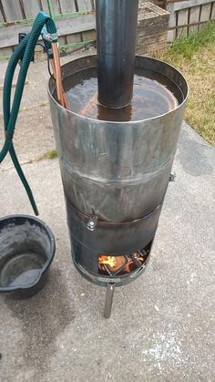 a large metal barrel sitting on top of a cement floor next to a fire pit