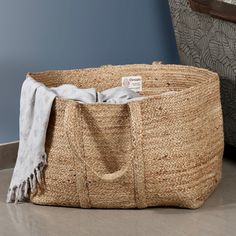 a large woven basket sitting on top of a wooden floor next to a gray chair