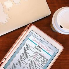 an open laptop computer sitting on top of a wooden table next to a coffee cup