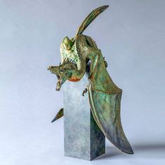 a sculpture of a dragon with its mouth open and wings spread out, sitting on top of a block