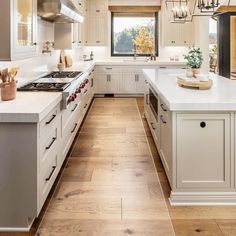 a large kitchen with white cabinets and wood flooring is seen in this image from the front view