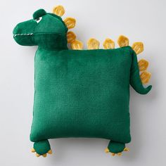 a green pillow with yellow flowers on the side and a stuffed animal in the middle