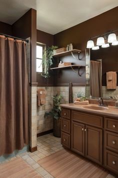 A cozy brown bathroom with tan tiles and wooden accents, creating a warm and inviting space. Brown Granite Bathroom Decor, Brown Cabinet Bathroom, Bathroom Remodel Brown Tones, Grey Brown Bathroom, Brown Bathroom Cabinets, Dark Brown Bathroom Ideas, Brown Tile Bathroom Ideas Color Palettes, Chocolate Brown Bathroom