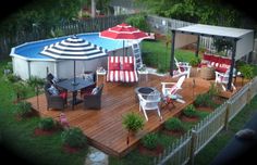 a deck with chairs and umbrellas next to a swimming pool in a backyard area