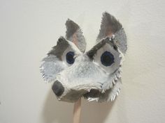 a paper animal mask on a stick with one eye open and the other half closed