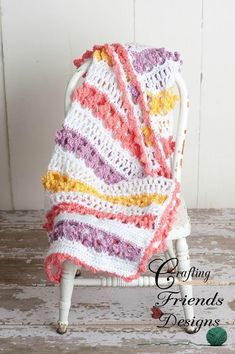 a crocheted blanket sitting on top of a white chair