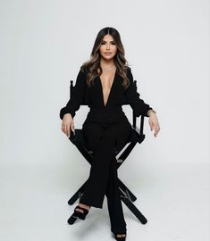 an image of a woman sitting in a chair with her legs crossed and wearing black