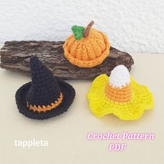 three crocheted witches hats sitting on top of a piece of wood