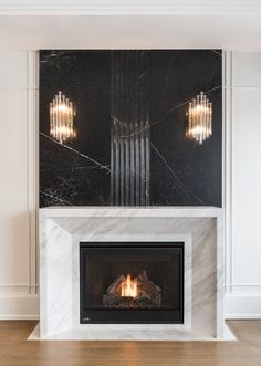 a fireplace with two lights on each side and a black marble mantle over the fire