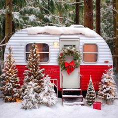 a red and white trailer parked in the snow next to trees with christmas wreaths on it