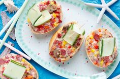 three small sandwiches on a plate with cheese and veggies in them, along with chopsticks