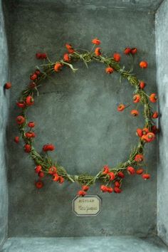 an arrangement of red flowers arranged in a circle on a cement wall with a plaque