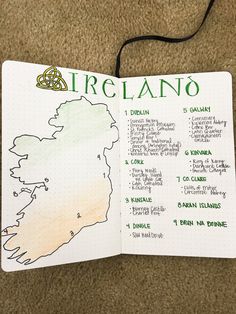 an open notebook with the map of ireland in green and white ink on top of brown carpet