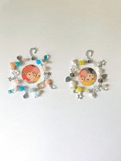 two earrings with pictures on them sitting next to each other in front of a white wall