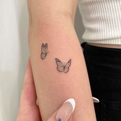 a woman's left arm with two butterflies on the back of her right arm