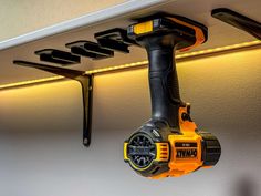 a cordless drill is hanging on the wall next to a shelf that has lights