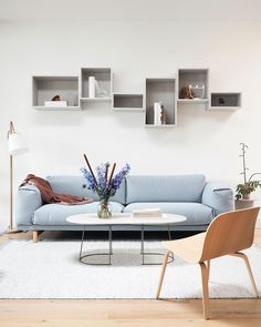 a living room with a blue couch and some shelves on the wall next to it