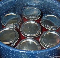 there are many empty glass jars in the pot with red liquid inside, and one is filled with water