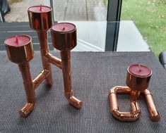 three copper candles sitting on top of a table next to a pair of glasses and a pipe